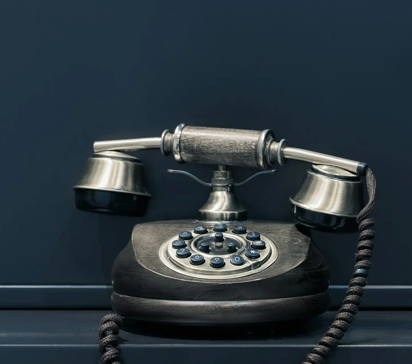 black and brown rotary phone near gray wall